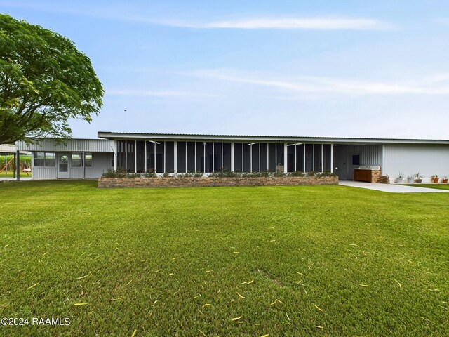 rear view of property with a sunroom and a lawn