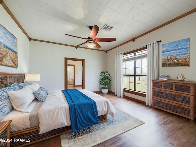 bedroom with crown molding, visible vents, a ceiling fan, connected bathroom, and wood finished floors