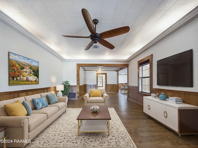 living room with ceiling fan, dark wood-style flooring, visible vents, ornamental molding, and wainscoting