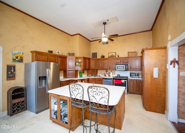 kitchen with a kitchen island, ceiling fan, a breakfast bar, and appliances with stainless steel finishes