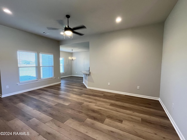 unfurnished living room with ceiling fan with notable chandelier and dark hardwood / wood-style floors