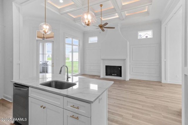 kitchen featuring white cabinets, stainless steel dishwasher, light wood-style flooring, a sink, and coffered ceiling