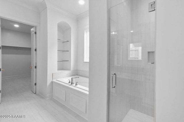 full bathroom with a bath, baseboards, a walk in closet, and a stall shower