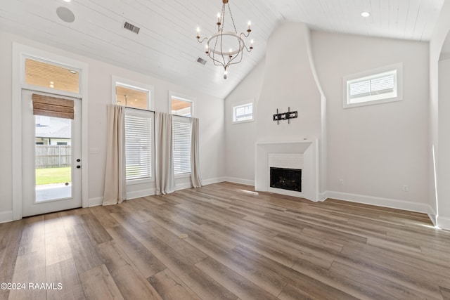 unfurnished living room featuring high vaulted ceiling, light hardwood / wood-style floors, and a notable chandelier