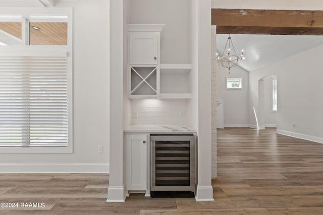 bar featuring vaulted ceiling with beams, backsplash, beverage cooler, hardwood / wood-style floors, and an inviting chandelier