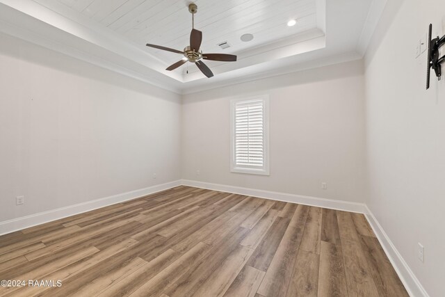 unfurnished room with ceiling fan, crown molding, a tray ceiling, and wood-type flooring