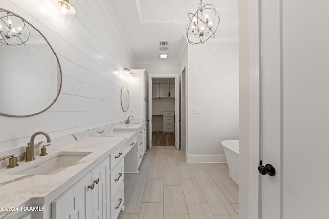 bathroom with hardwood / wood-style floors, a tub to relax in, ornamental molding, vanity, and a chandelier