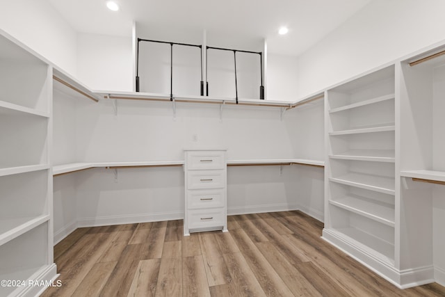 walk in closet with light wood-type flooring and built in desk