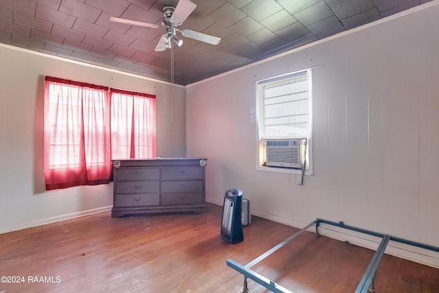 unfurnished bedroom featuring cooling unit, ceiling fan, hardwood / wood-style flooring, and crown molding