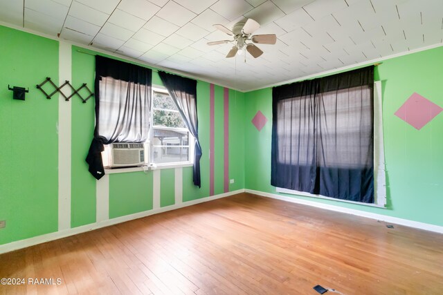 empty room featuring ornamental molding, hardwood / wood-style floors, cooling unit, and ceiling fan