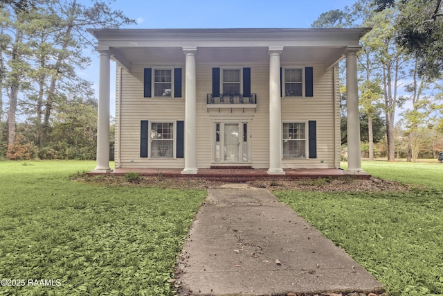 greek revival house featuring a balcony and a front lawn