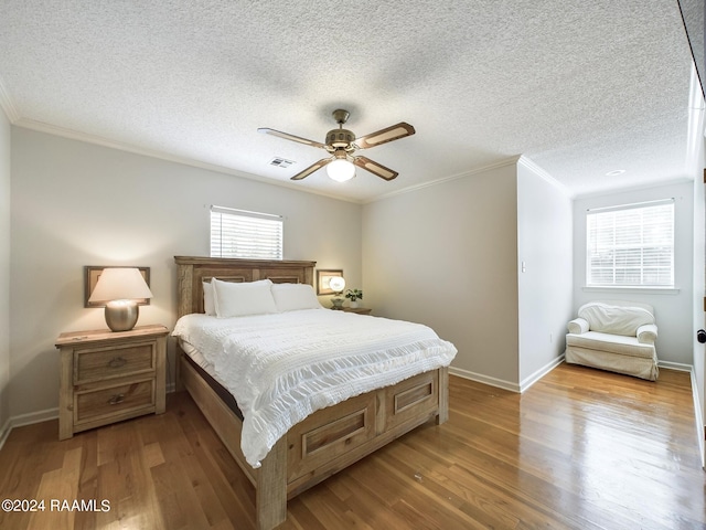 bedroom featuring multiple windows, a textured ceiling, hardwood / wood-style flooring, and ceiling fan