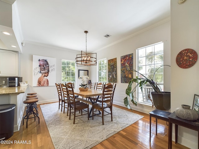 dining area with ornamental molding, plenty of natural light, an inviting chandelier, and hardwood / wood-style floors