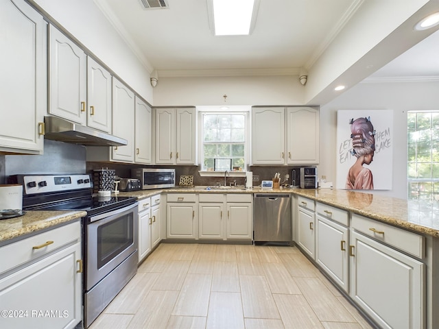 kitchen with crown molding, appliances with stainless steel finishes, plenty of natural light, and backsplash