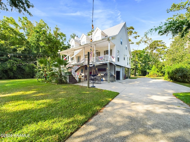 back of property with covered porch and a lawn