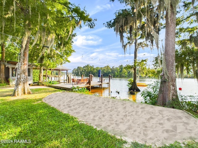 surrounding community featuring a water view, a lawn, and a boat dock