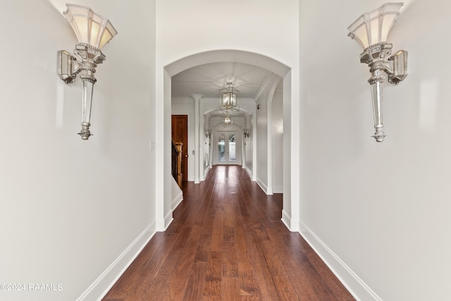 hallway featuring crown molding, dark hardwood / wood-style floors, and a notable chandelier