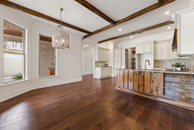 kitchen featuring dark hardwood / wood-style flooring, pendant lighting, backsplash, beam ceiling, and light stone counters