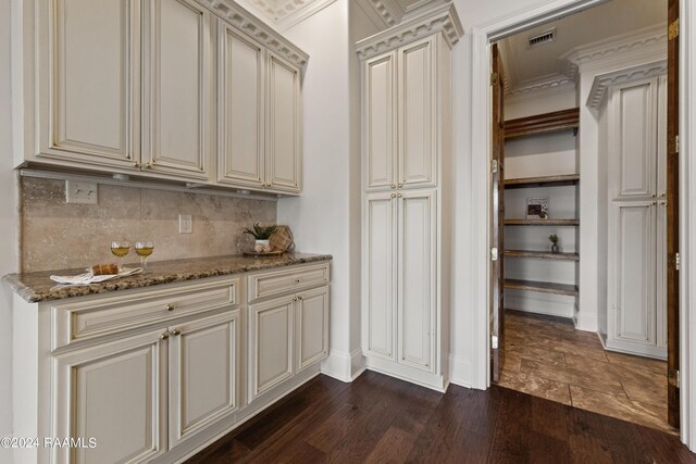 kitchen with cream cabinetry, ornamental molding, dark hardwood / wood-style flooring, and stone counters