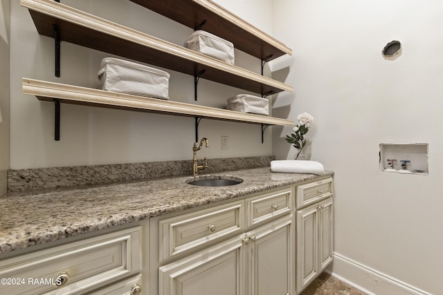 washroom with cabinet space, washer hookup, baseboards, and a sink