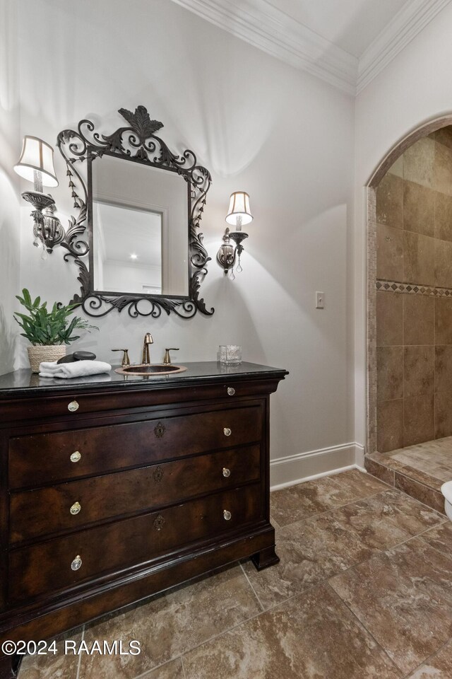 bathroom featuring tiled shower, vanity, and ornamental molding