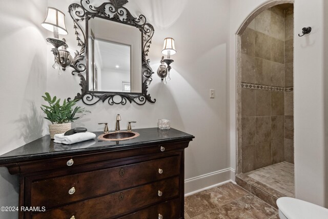 bathroom featuring vanity, toilet, baseboards, and a tile shower