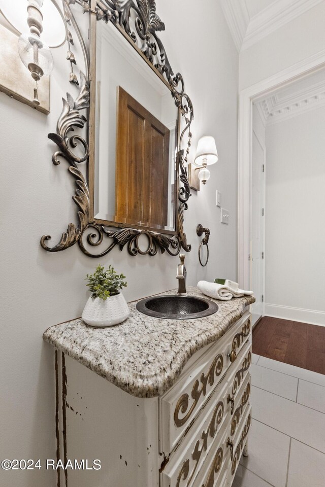 bathroom featuring baseboards, wood finished floors, ornamental molding, and vanity