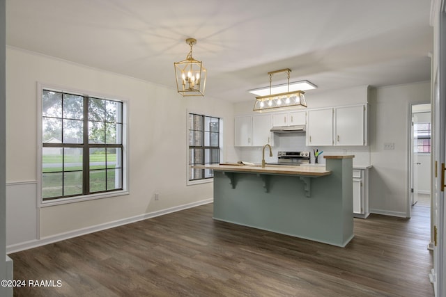 kitchen featuring white cabinets, a kitchen bar, hanging light fixtures, and dark hardwood / wood-style floors