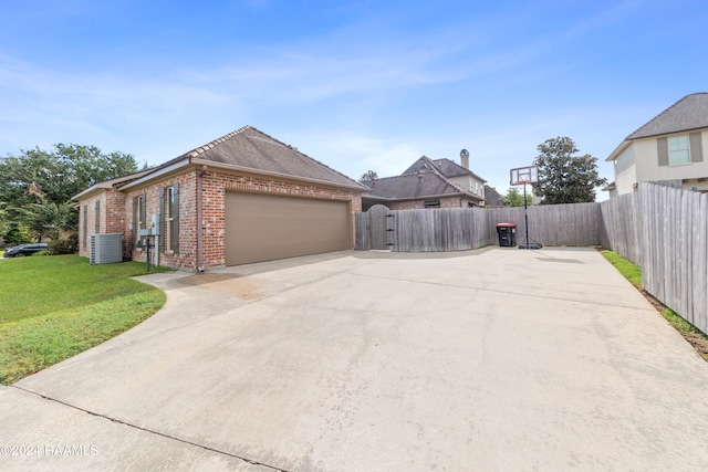 view of front of home featuring a front lawn, a garage, and central AC