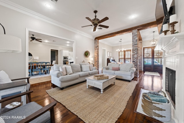 living room with hardwood / wood-style floors, ceiling fan with notable chandelier, brick wall, a premium fireplace, and ornamental molding