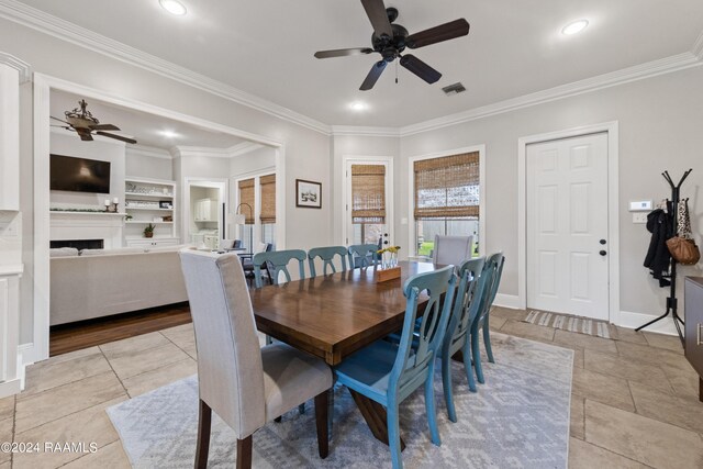 dining room featuring built in shelves, ceiling fan, ornamental molding, and light tile patterned flooring