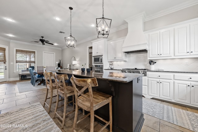 kitchen with ceiling fan with notable chandelier, stainless steel appliances, a breakfast bar area, a kitchen island, and decorative backsplash