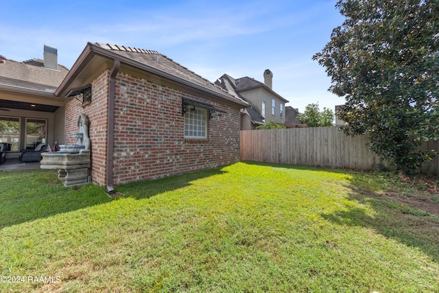 view of side of home with a lawn and a patio