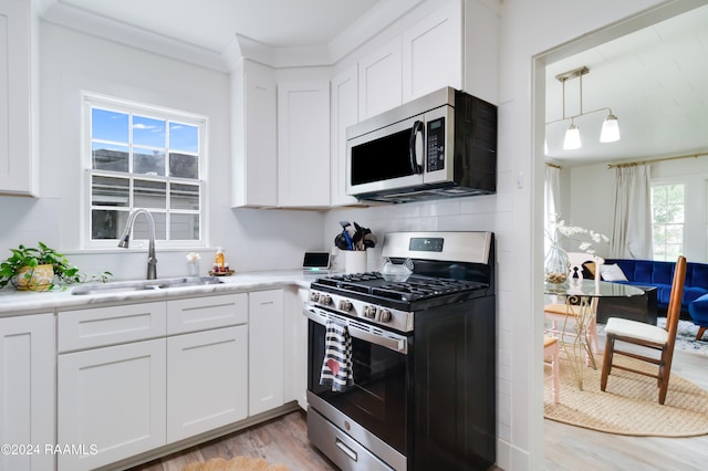 kitchen with a wealth of natural light, appliances with stainless steel finishes, and white cabinets