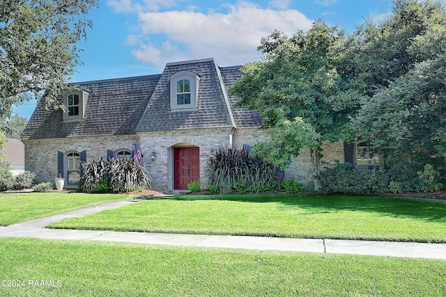 view of front of home featuring a shingled roof, a front yard, brick siding, and mansard roof