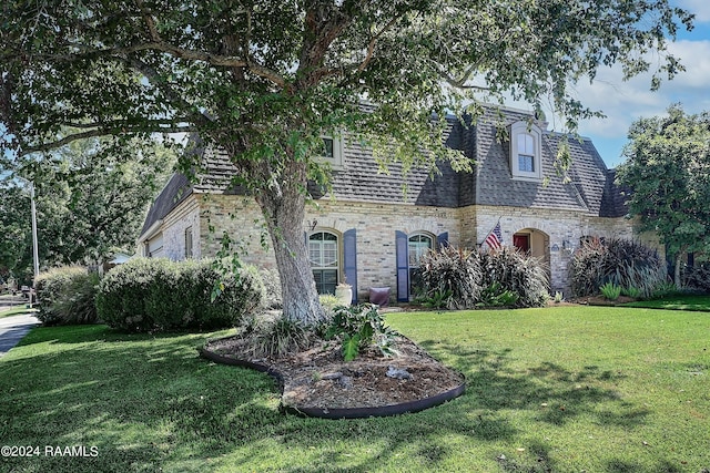 view of front facade with roof with shingles and a front lawn