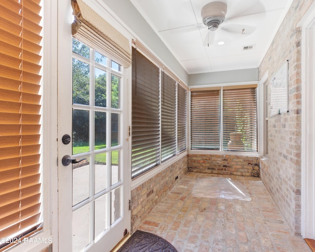 unfurnished sunroom featuring a wealth of natural light, visible vents, and ceiling fan