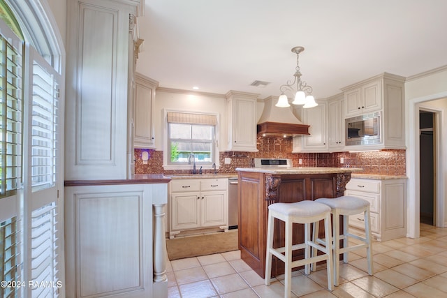 kitchen featuring premium range hood, visible vents, appliances with stainless steel finishes, decorative backsplash, and a center island