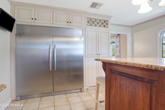 kitchen featuring built in fridge, visible vents, ornamental molding, light tile patterned flooring, and light stone countertops