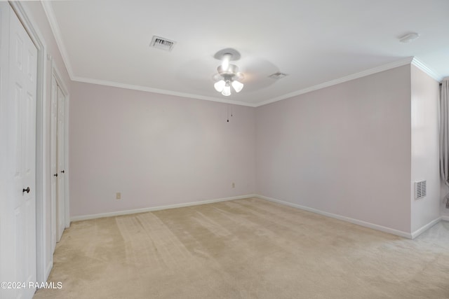 empty room featuring ornamental molding, light colored carpet, and visible vents