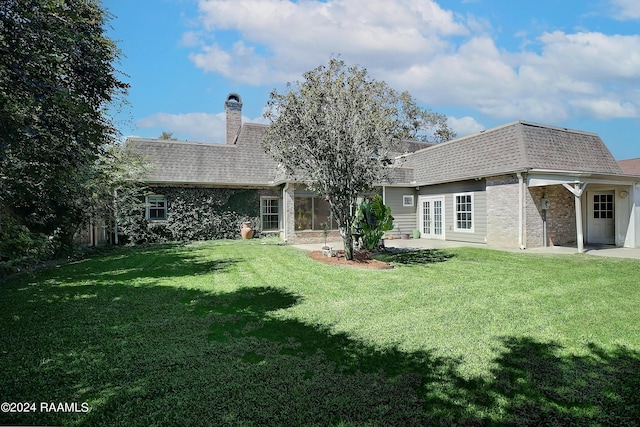 rear view of property with a yard, french doors, roof with shingles, and brick siding