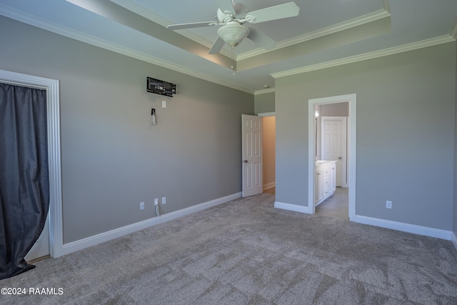 unfurnished bedroom with light colored carpet, ceiling fan, ornamental molding, and a tray ceiling