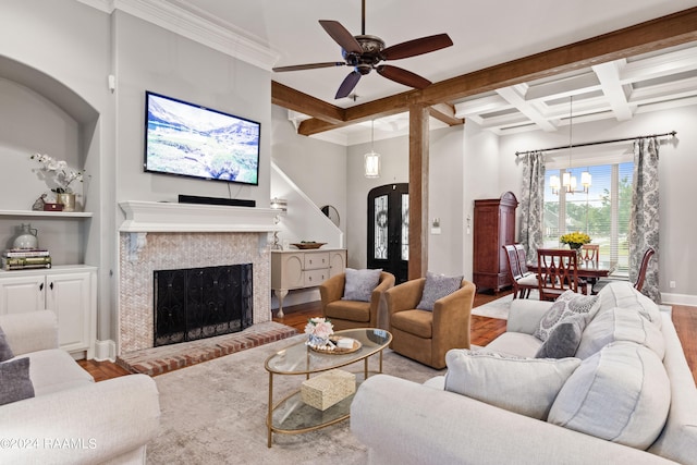 living room with coffered ceiling, ceiling fan with notable chandelier, light wood-type flooring, and a fireplace