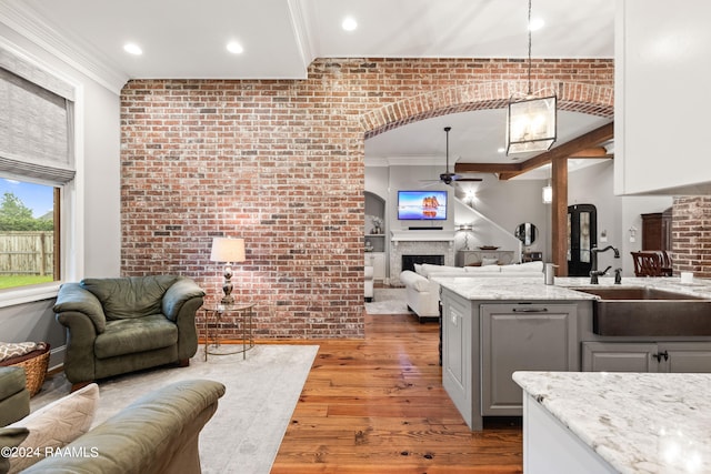 kitchen with pendant lighting, light hardwood / wood-style flooring, brick wall, and ceiling fan