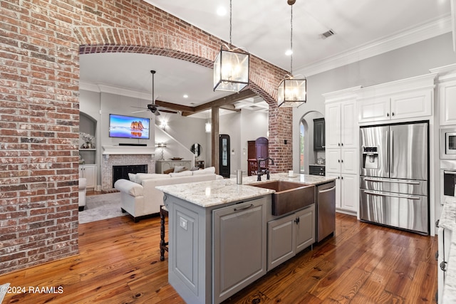 kitchen featuring white cabinetry, an island with sink, light stone countertops, dark hardwood / wood-style floors, and appliances with stainless steel finishes