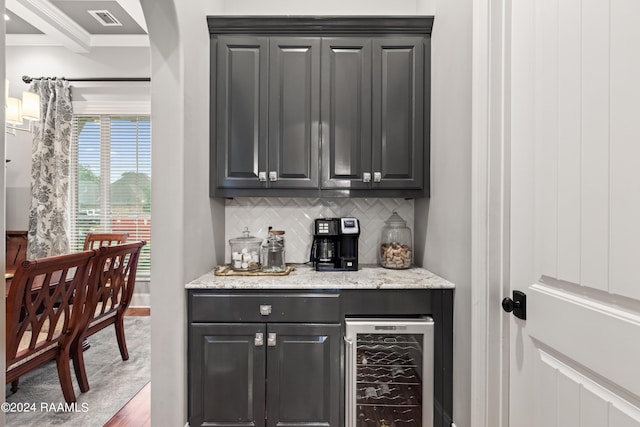 bar with beverage cooler, backsplash, light stone counters, and crown molding