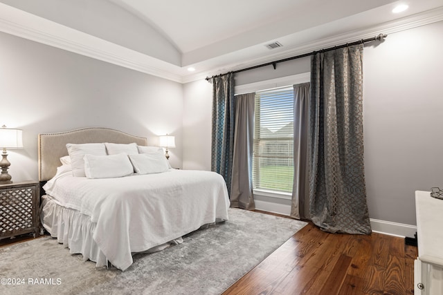 bedroom with vaulted ceiling, ornamental molding, and hardwood / wood-style flooring