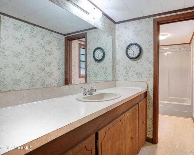 bathroom with crown molding, vanity, and a bathtub