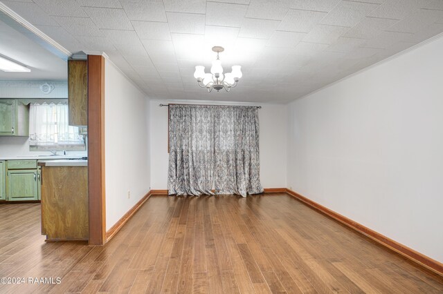 unfurnished dining area featuring crown molding, an inviting chandelier, and light wood-type flooring