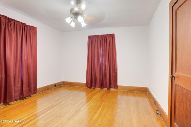 empty room with ceiling fan and light hardwood / wood-style flooring